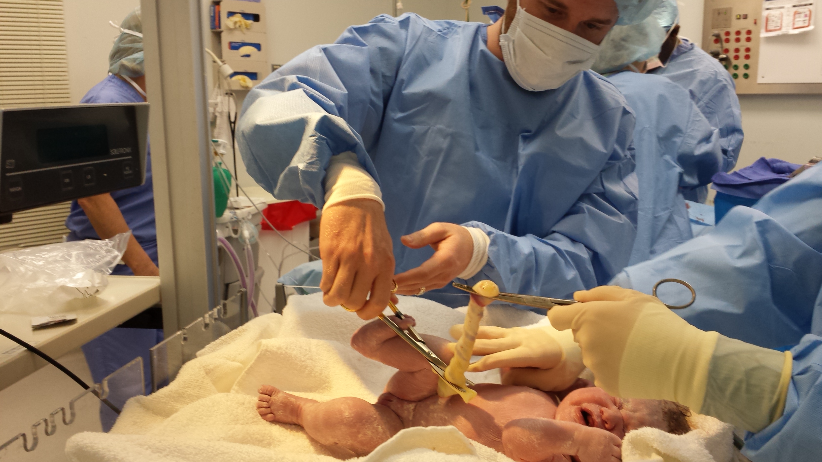 Gregory cutting the umbilical cord as Nurse Deborah takes photos