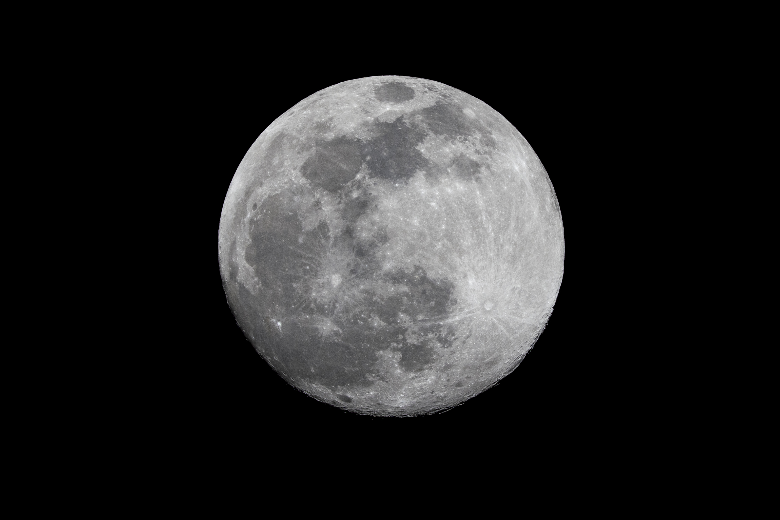 a full moon in the dark sky with a plane flying in front of it and a black sky background