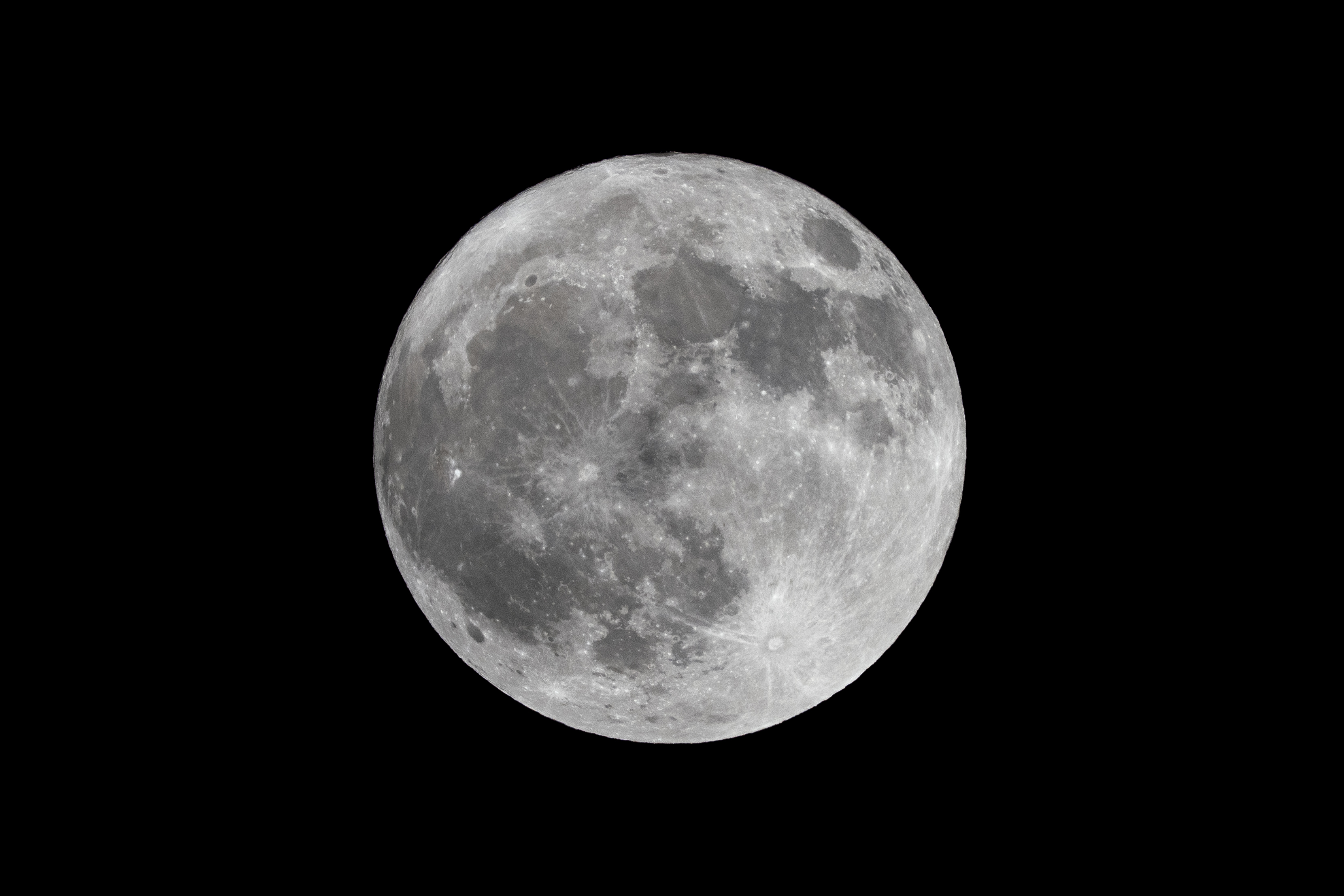a full moon in the dark sky with a plane flying in front of it and a black sky background