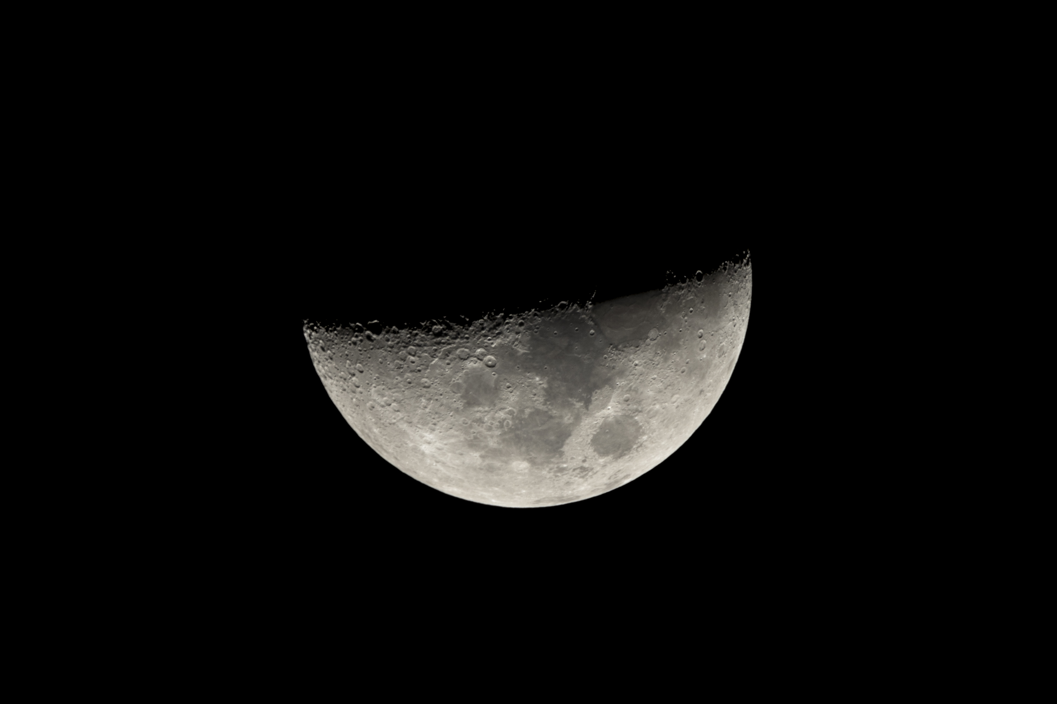 a half moon in the dark sky with a few clouds in the foreground and a black sky with a few clouds in the background